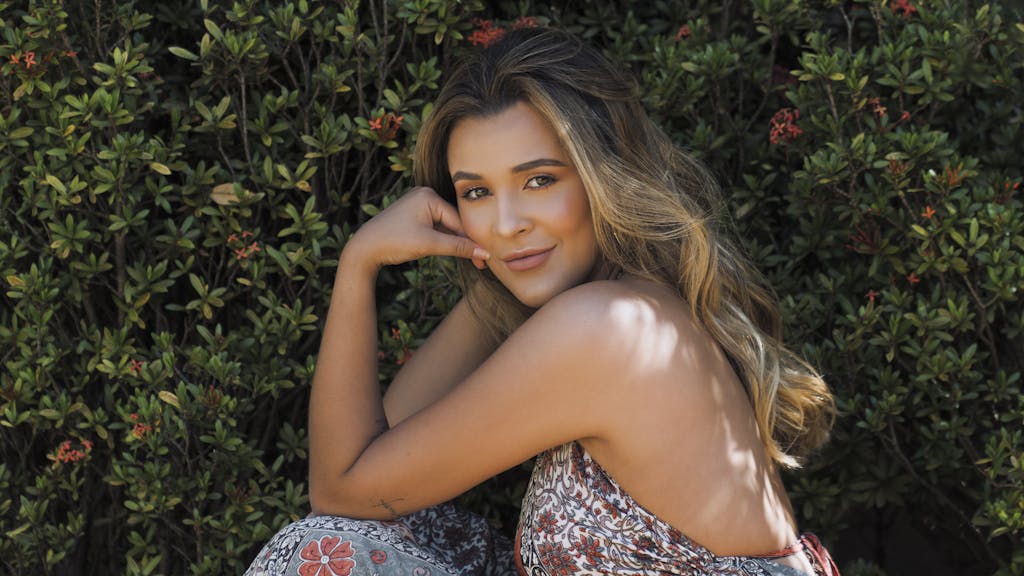 Beautiful A beautiful young woman posing and smiling next to vibrant bushes outdoors in Brazil.