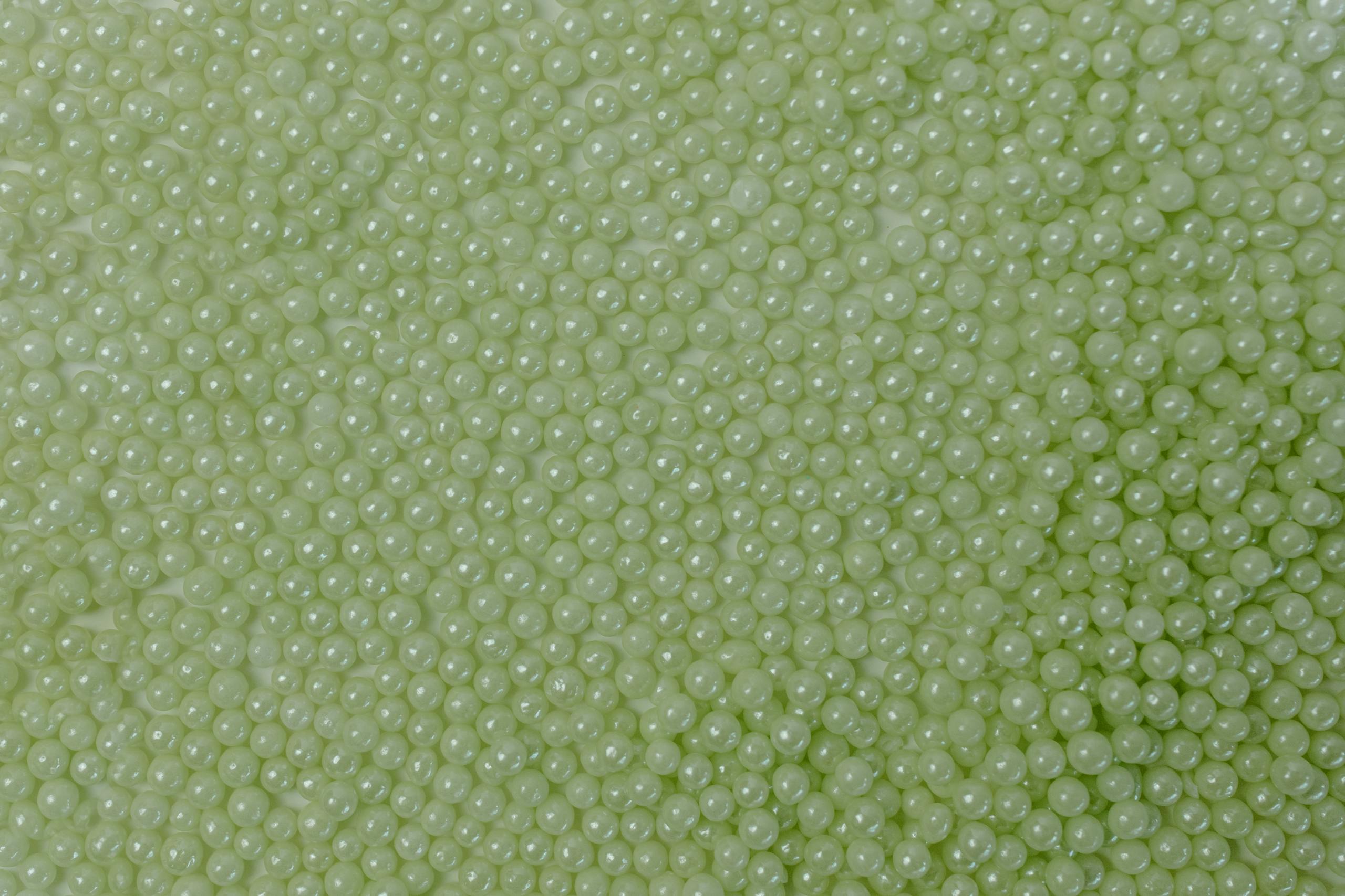 Bin Matcha A close-up of green candy spheres creating a vibrant, textured background.