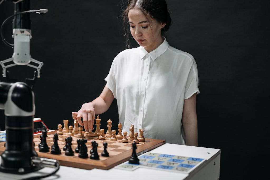 <!-- wp:separator -->
<hr class="wp-block-separator has-alpha-channel-opacity"/>
<!-- /wp:separator --> A woman plays chess with a robotic arm, illustrating technology and strategy in a modern context.