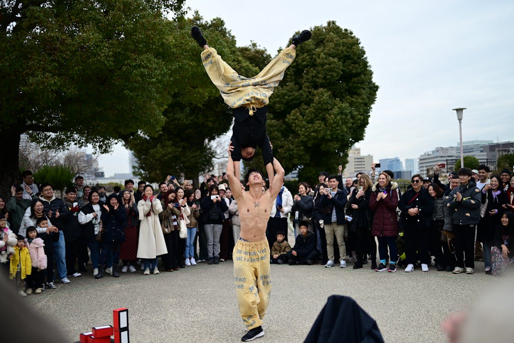 Wynonna Judd Performance Reactions Acrobatic performers captivating an outdoor audience with skillful stunts in a lively street show.