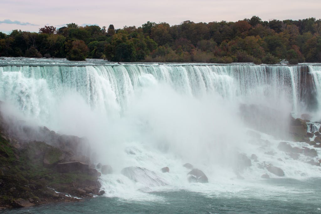 TheGlobeAndMail Breathtaking view of Niagara Falls surrounded by autumn foliage and mist.