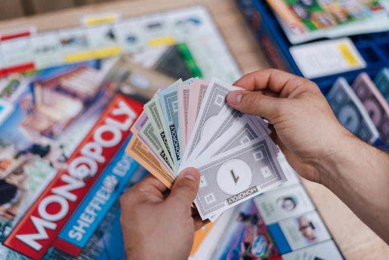 Florida Woman Wins Monopoly Lottery From above of crop anonymous man with set of game money playing Monopoly above board