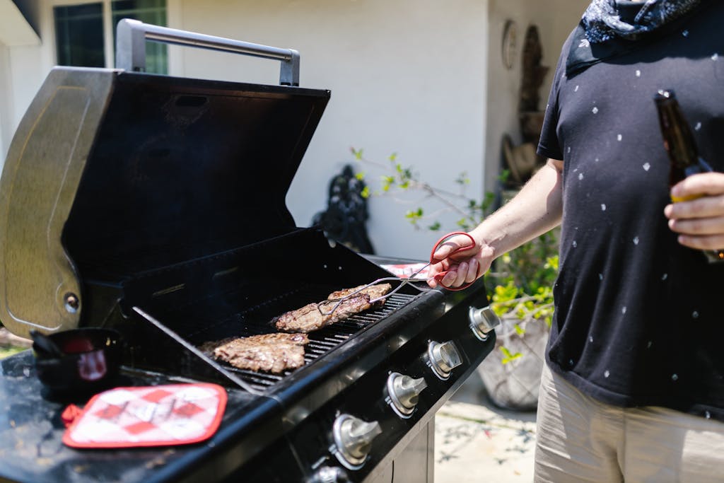 Weber Grillvorführung Person grilling steaks on barbecue outdoors, enjoying a sunny day.