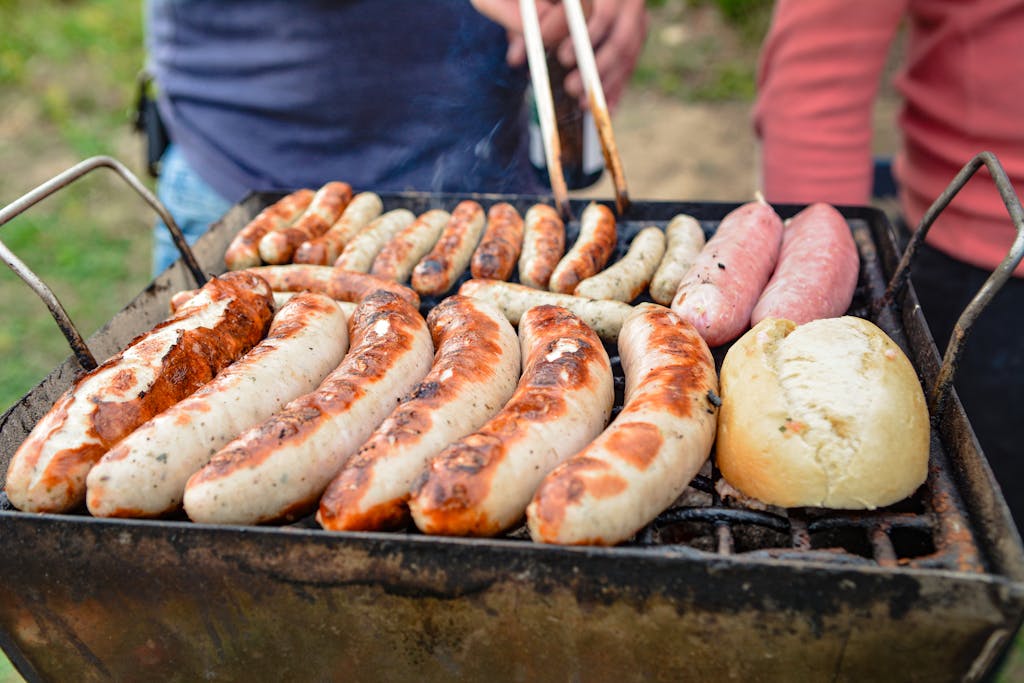 Weber Grillvorführung Sizzling barbecue with grilled sausages and bread outdoors during a cookout.