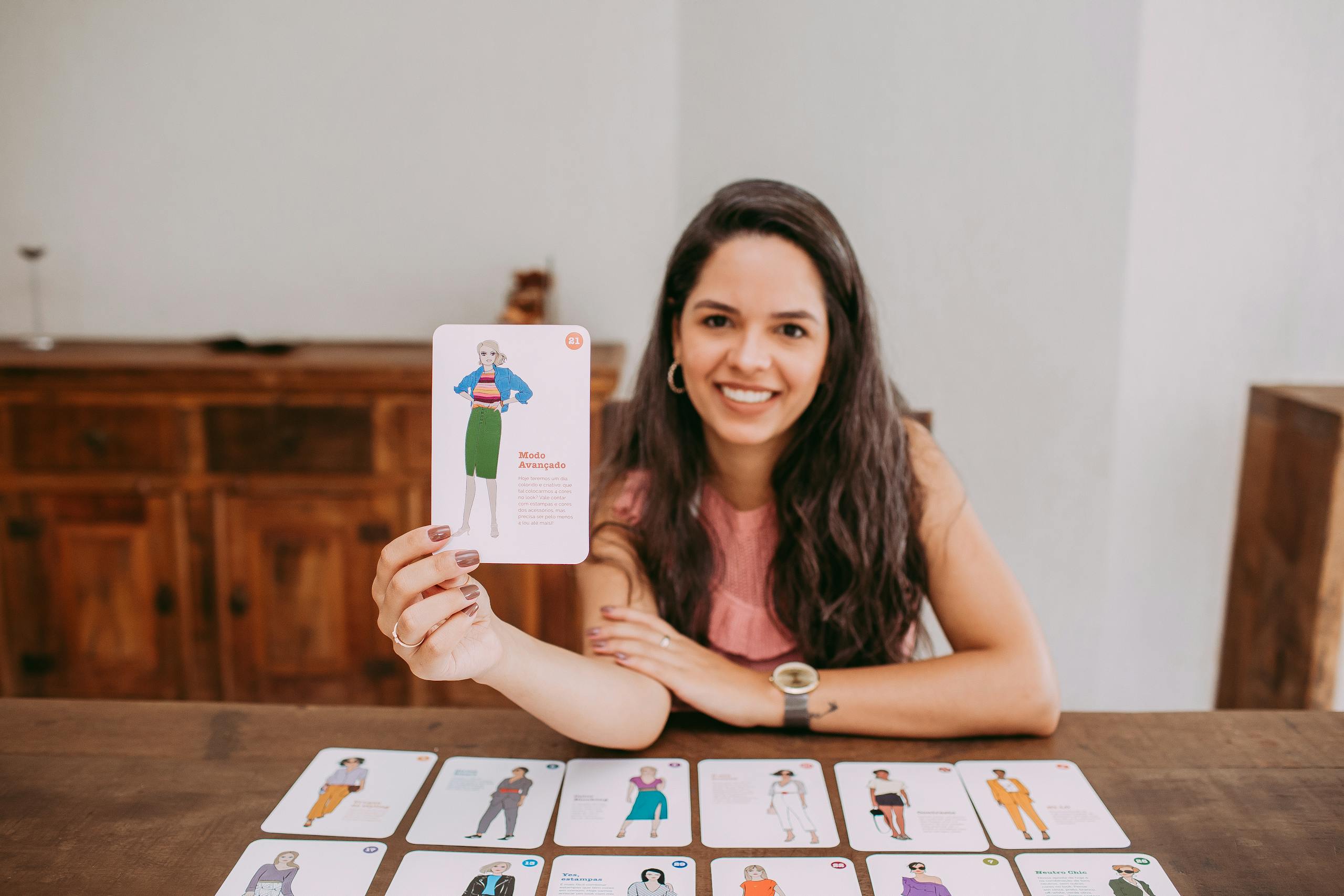 JoinMyQuiz Smiling woman presenting educational flashcards at a wooden table indoors.