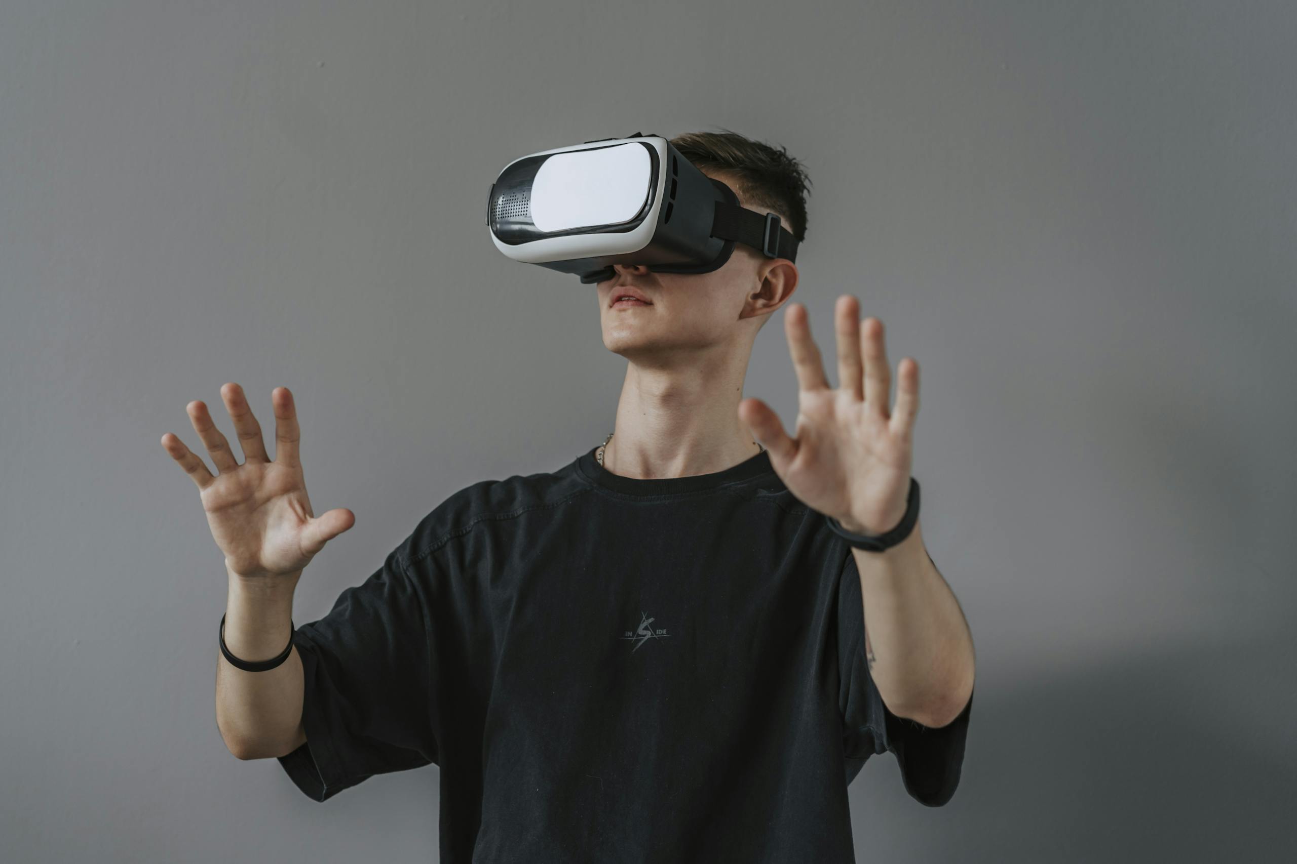 Sixmagazine Young man explores virtual reality with VR headset, hands raised.