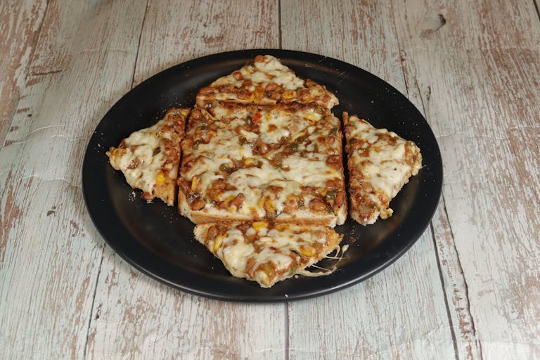 ChatPic A close-up view of cheesy pizza slices on a black plate, set on a rustic wooden table, perfect for food blogs.