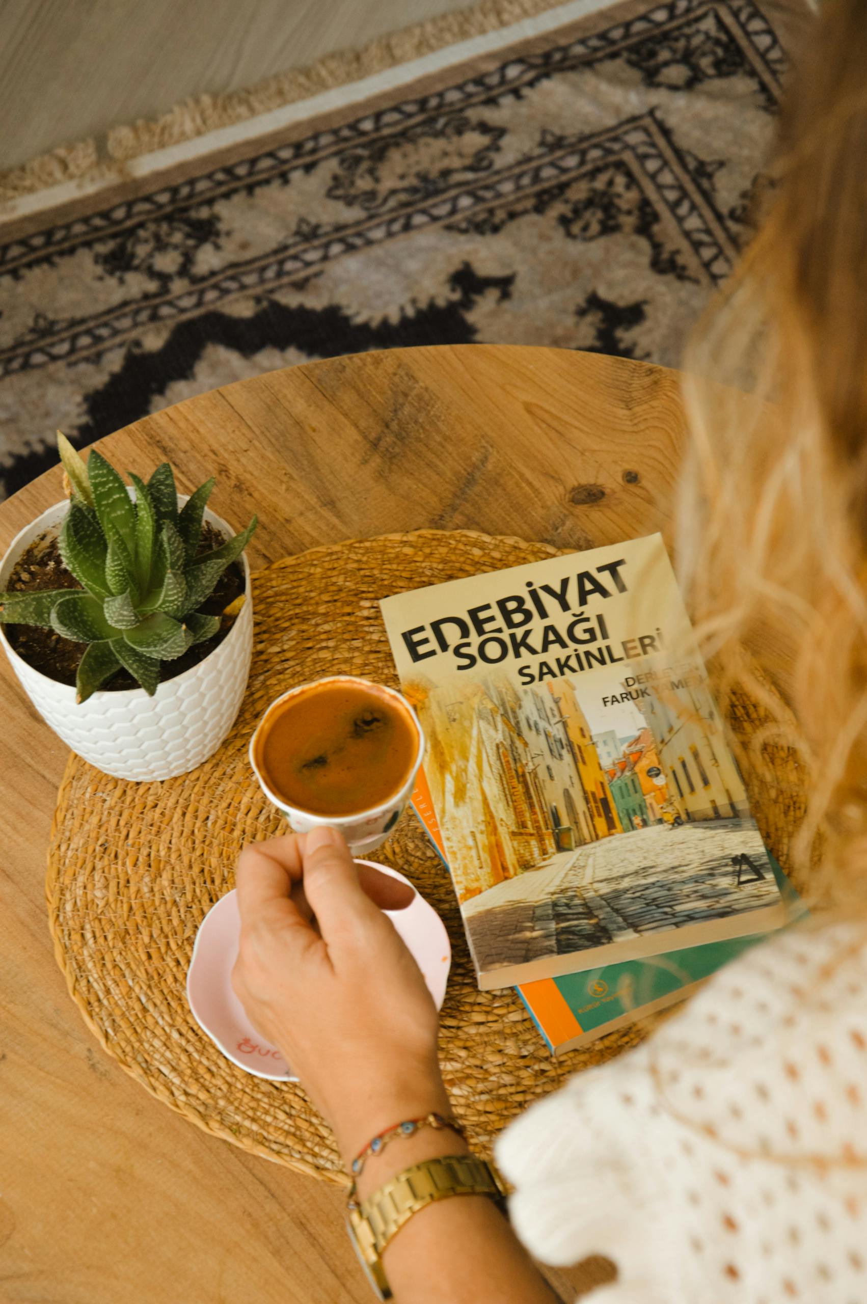 Veb Vatsap Com A cozy setup with coffee, a book, and a potted plant on a wooden table.