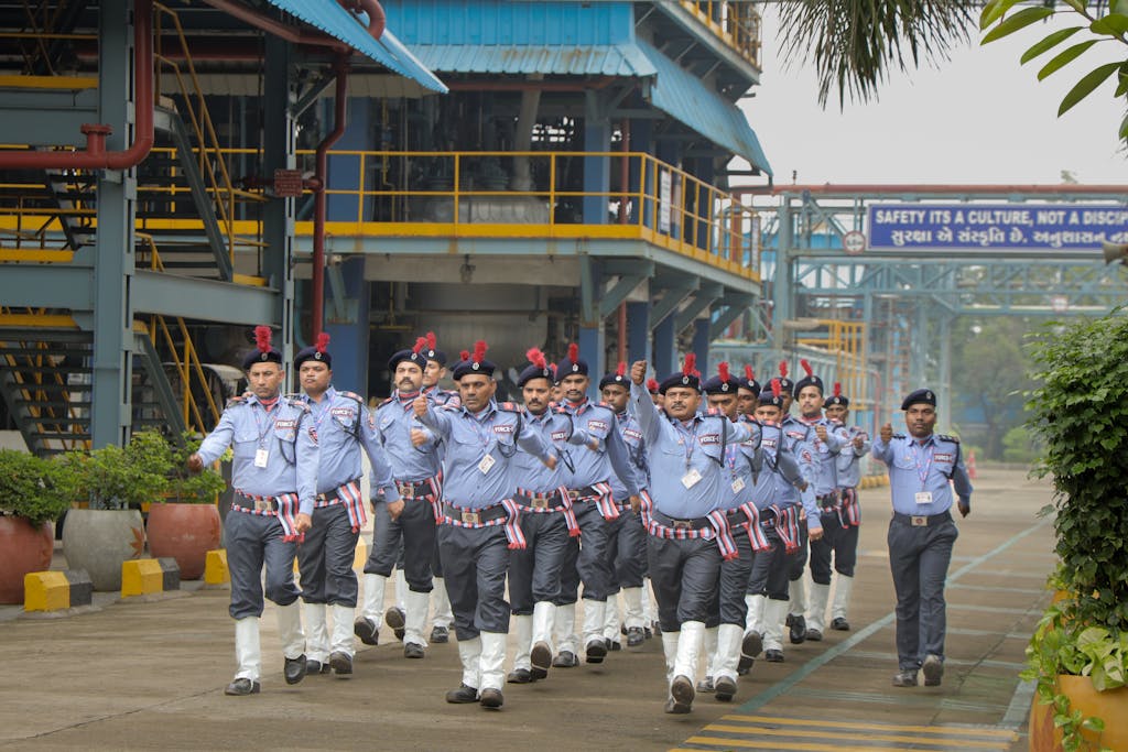 rajkot updates news A group of security guards marching in an industrial area, showcasing discipline and teamwork.