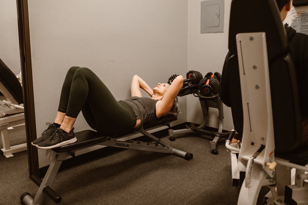 Bottlecrunch Adult woman exercising on a bench in a gym, promoting fitness and healthy lifestyle.