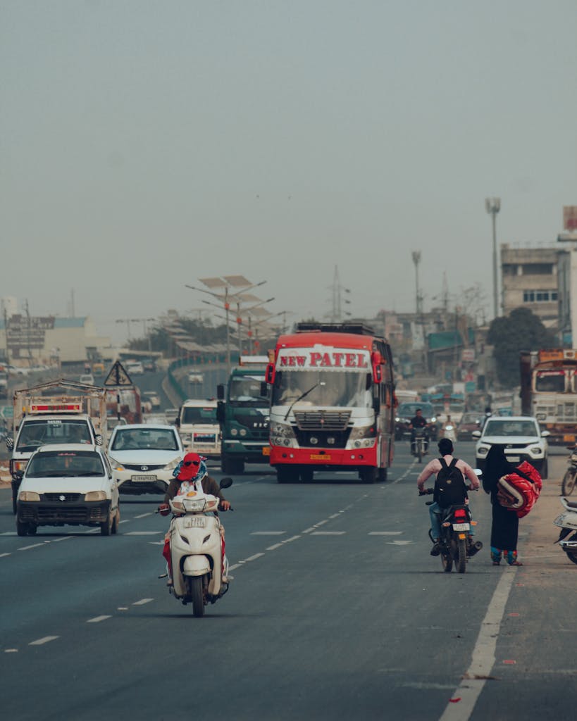 rajkot updates news City street in India with vehicles and pedestrians under smoggy skies, showcasing urban transportation.