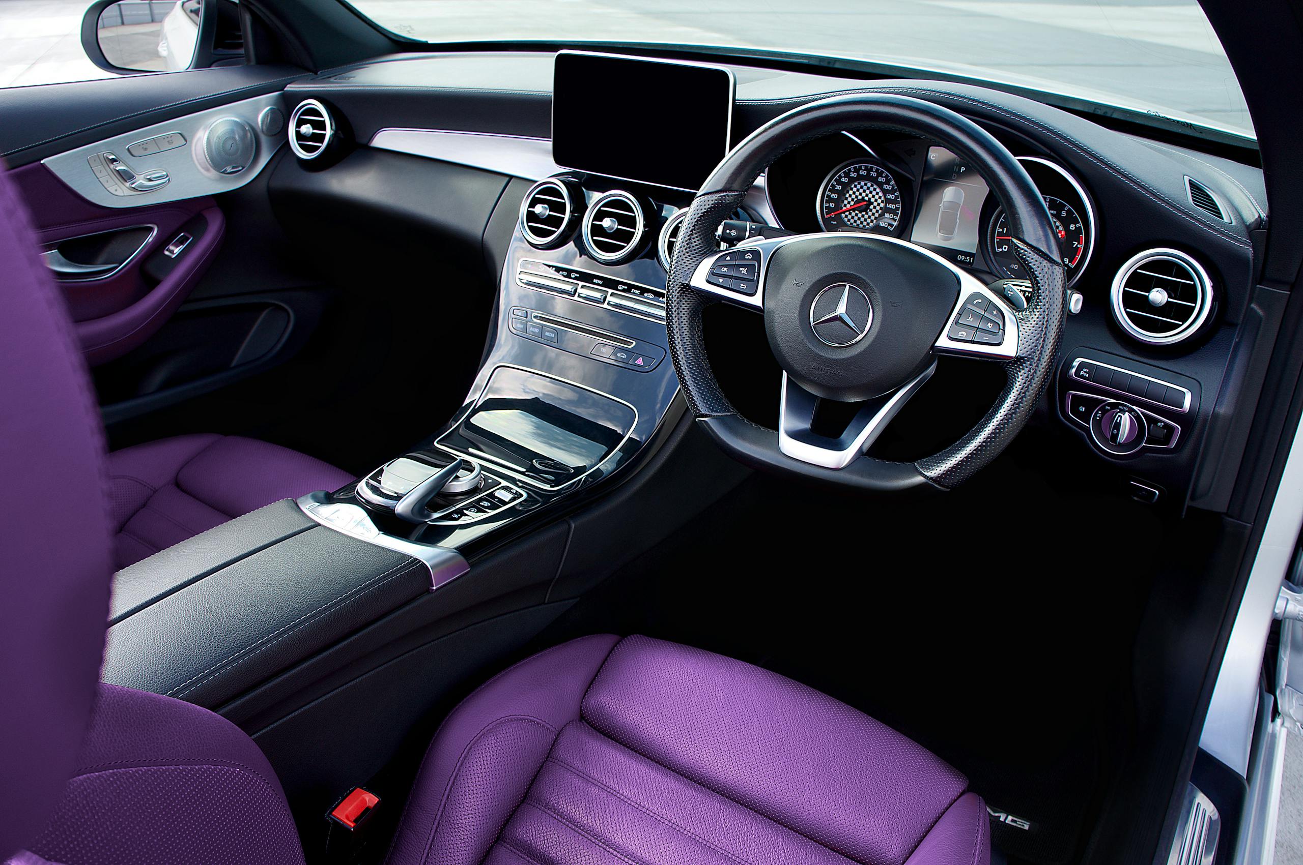 Luxury Car Rental UK Interior view of a Mercedes Benz showing luxury steering wheel and purple leather seats.
