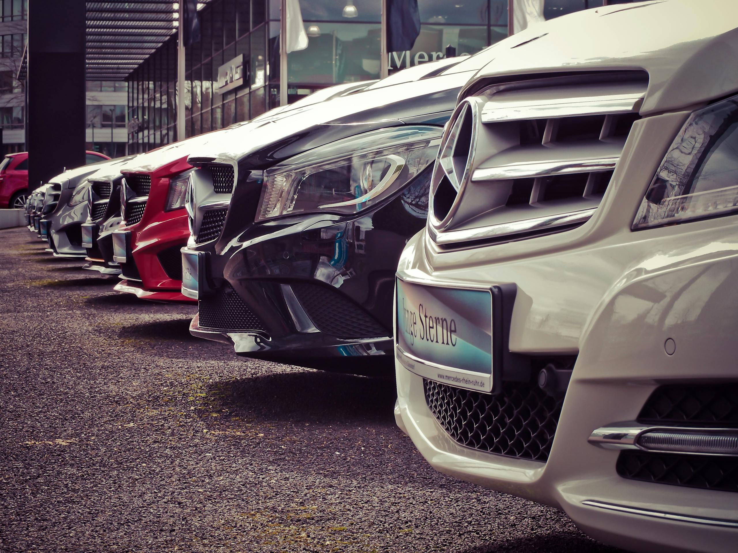 Monthly Car Rental Bahrain Luxury cars lined up at an outdoor dealership, showcasing sleek designs.
