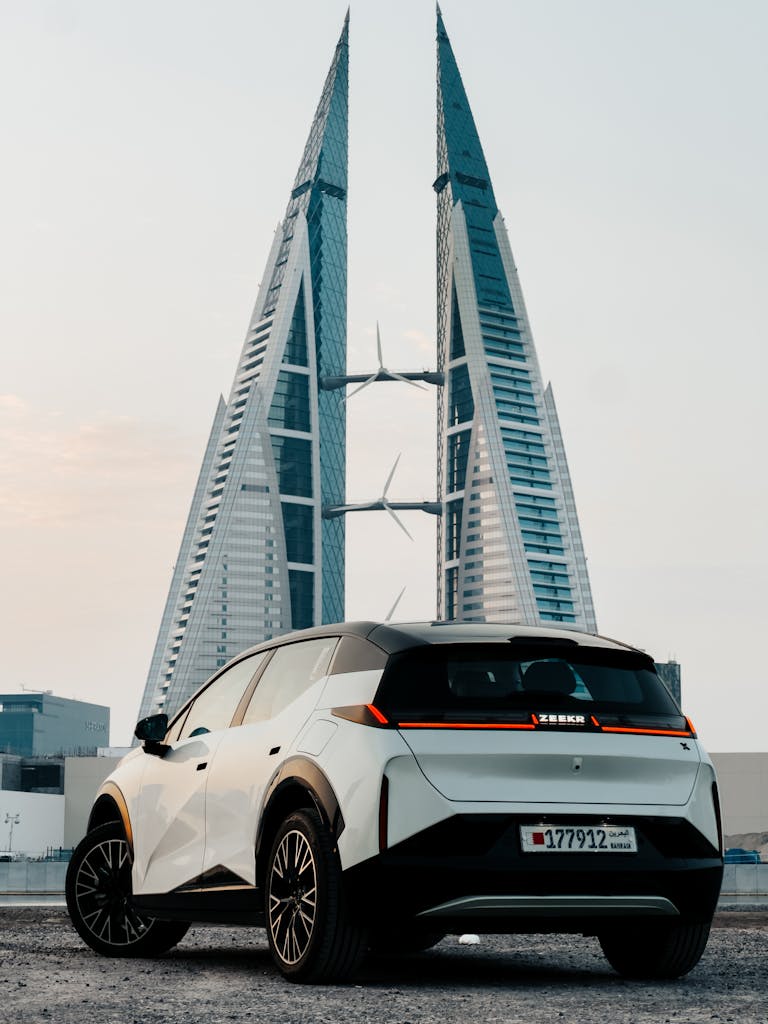 Monthly Car Rental Bahrain Sleek electric SUV parked near the iconic Bahrain World Trade Center, showcasing modern design.