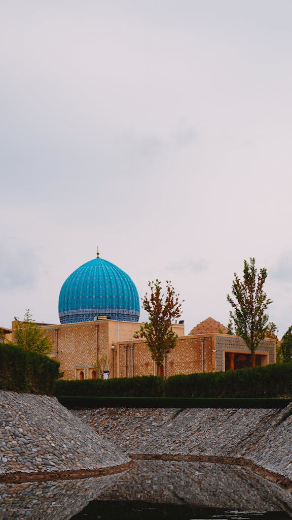Voozon Stunning blue dome of a historical mosque in Samarkand, Uzbekistan, surrounded by lush greenery.