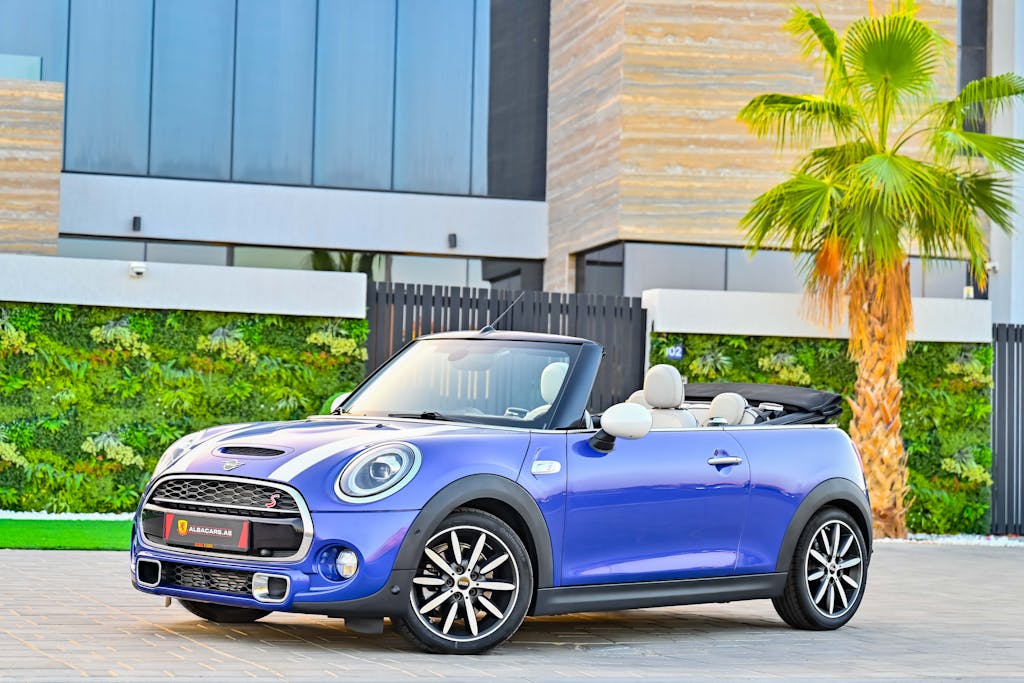 Luxury Car Rental UK Stylish blue Mini Cooper convertible car parked in sunny Dubai neighborhood.