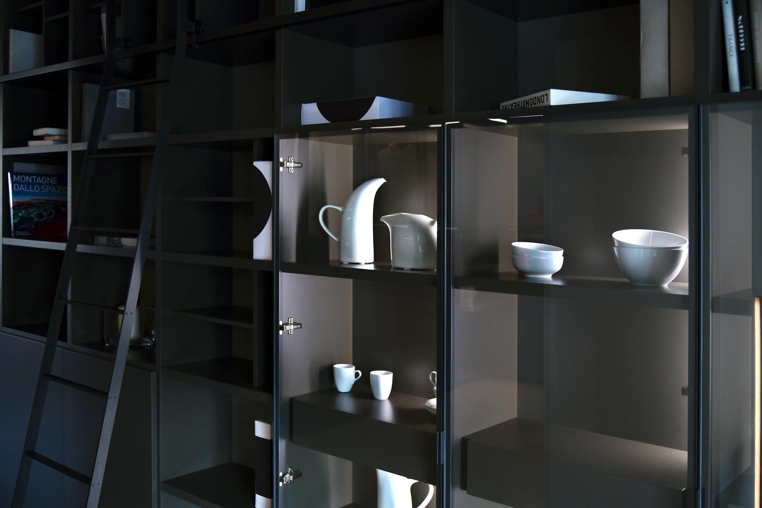 Memorandum to Cabinet Stylish display of white ceramic tableware on dark shelving in contemporary setting.