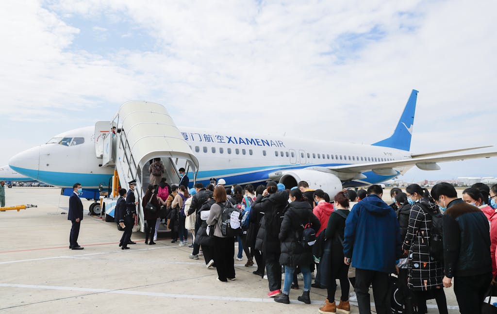 openskynews Travelers at an airport embarking a XiamenAir plane on a clear day.